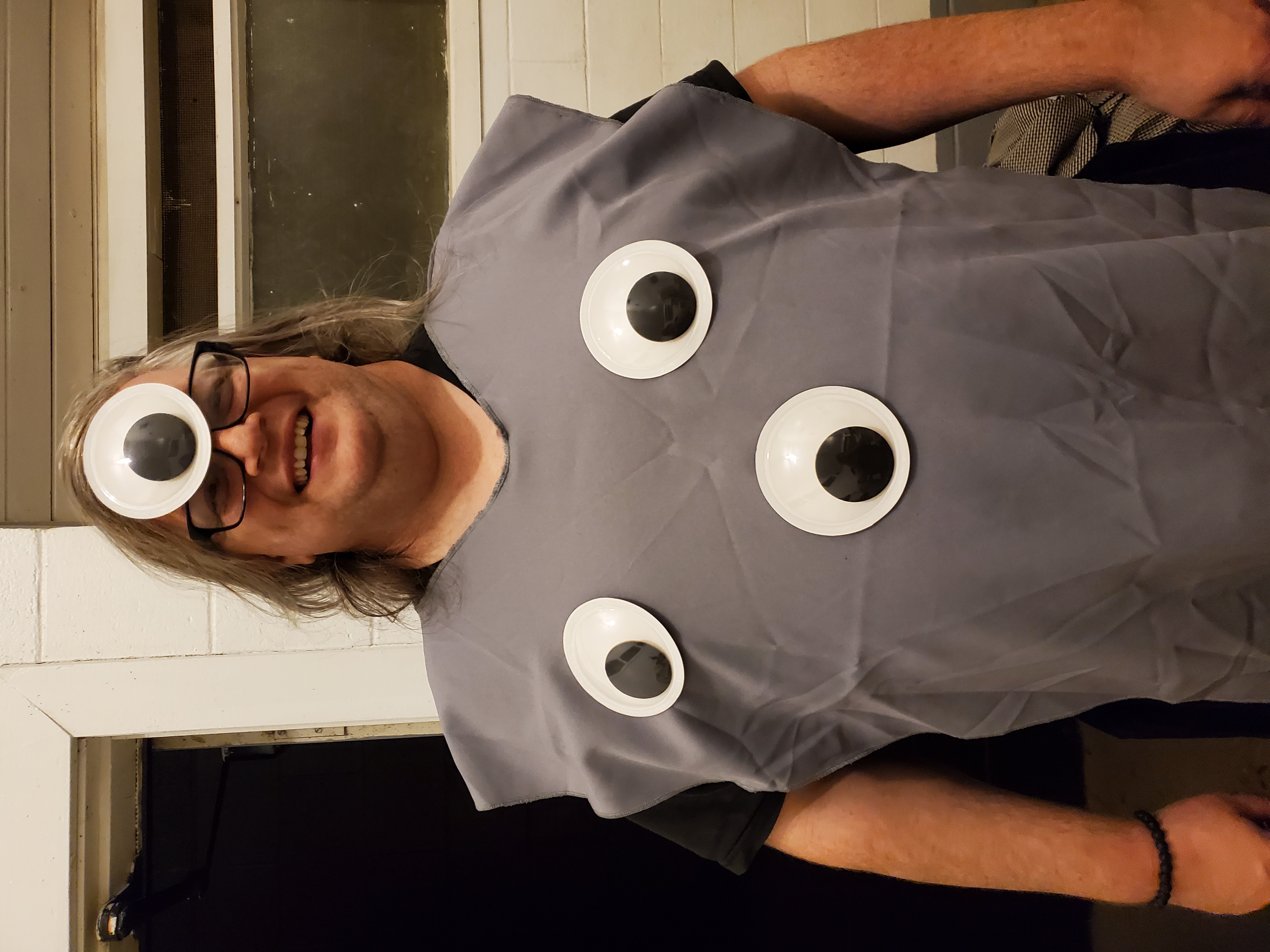A lovely human wearing a grey tabard and googly eyes, photo by Barbara M